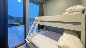 A bunk bed with a ladder, a window with a view of a body of water and hills, and a plain wall. - 3 bedroom lovely home in Lindesnes (Lindesnes)
