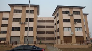 A multi-story building with a flat roof, air conditioning units, and a satellite dish.