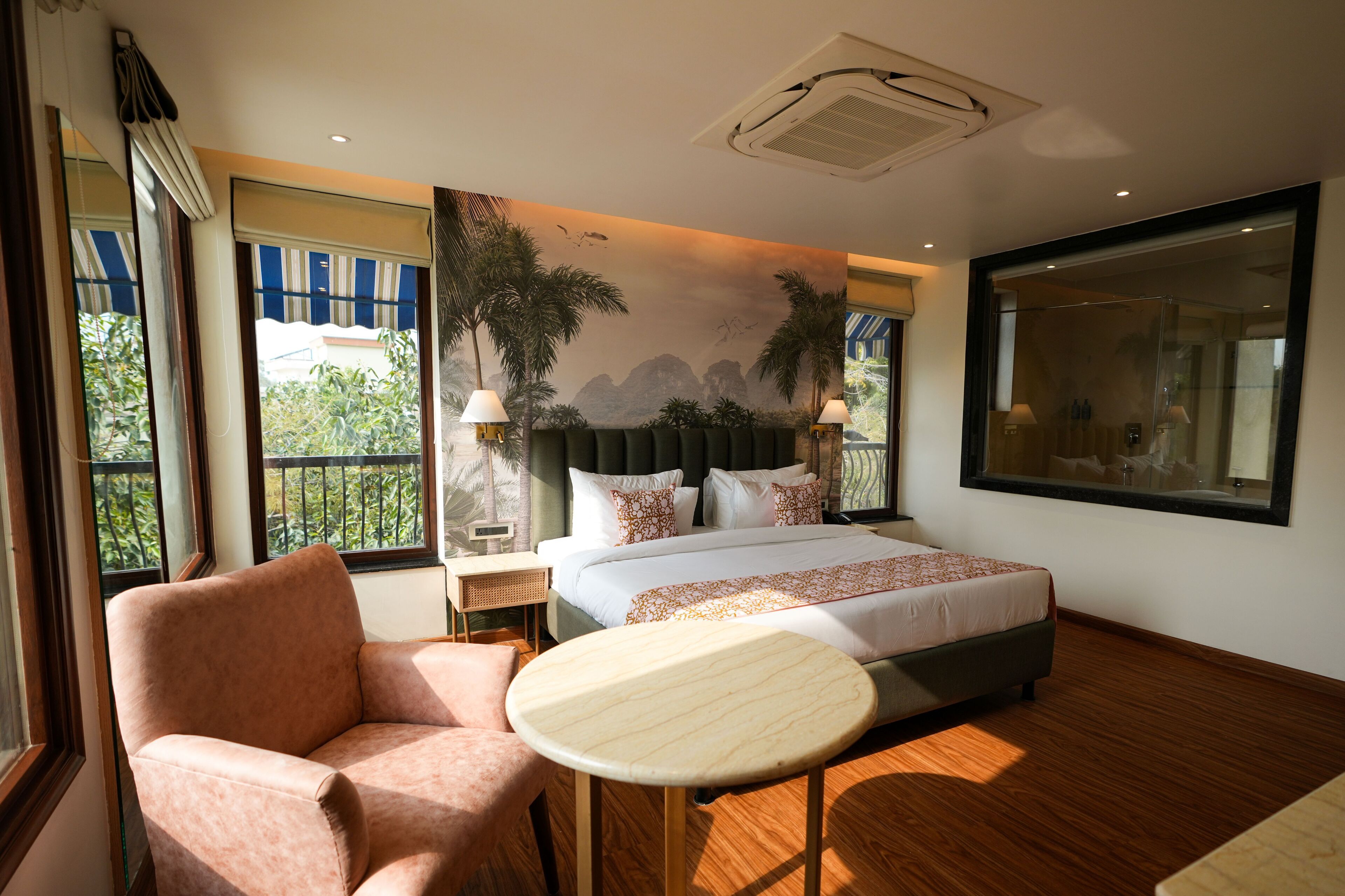 Un dormitorio con una cama, una silla, una mesita y un ventanal grande.