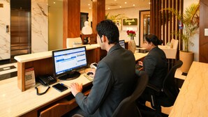 A hotel reception desk with a computer, a telephone, and a QR code sign.