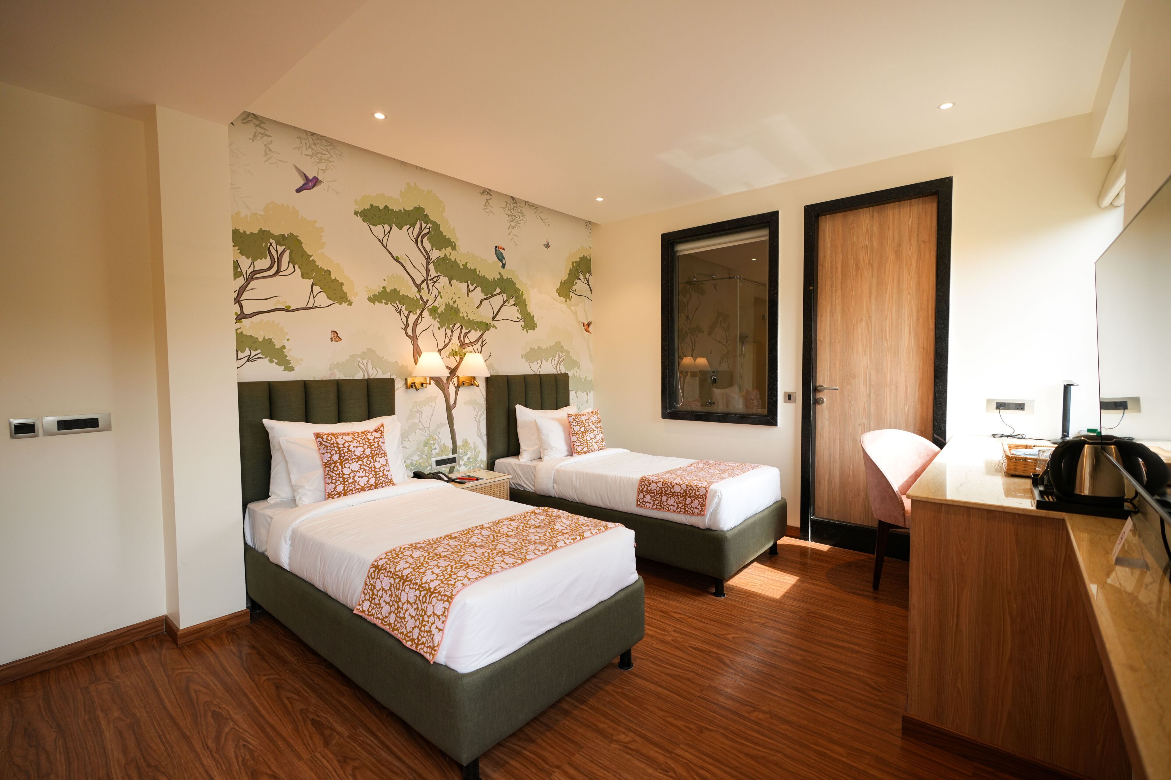 Habitación de hotel con dos camas, un escritorio y un espejo grande.