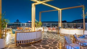 An outdoor dining area with tables and chairs, a bar area, and potted plants.