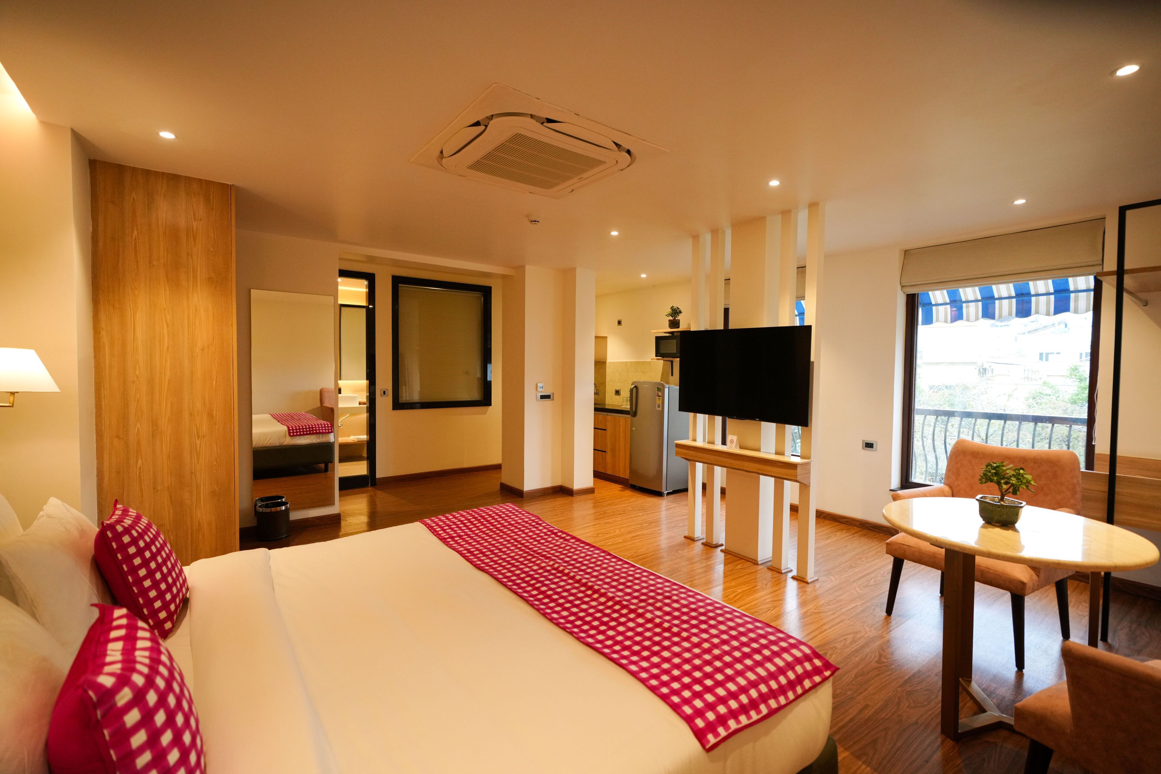 Habitación de hotel con cama, televisión, mesa de comedor y balcón con vistas.
