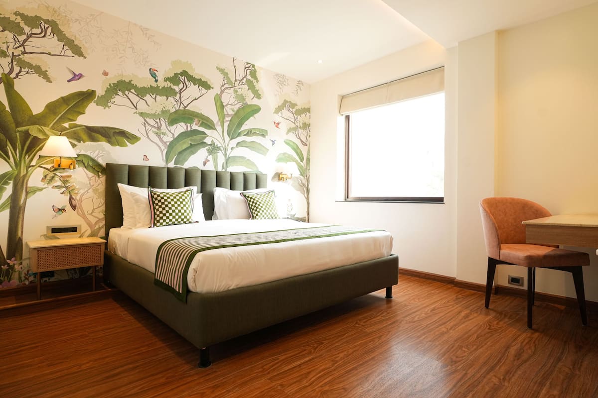 Un dormitorio con cama, mesita de noche, lámpara, sillón y ventana.