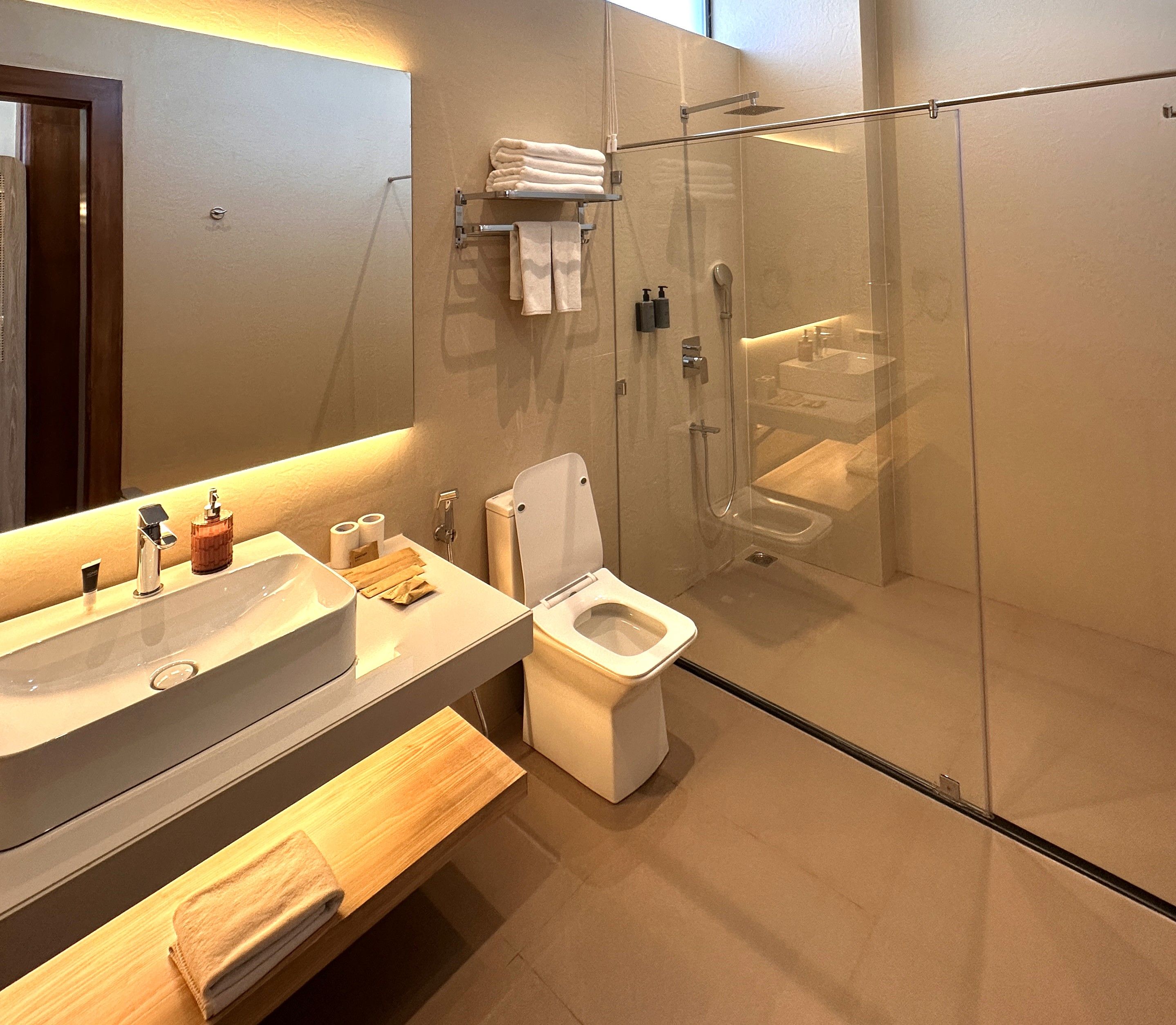 A modern bathroom with a glass-enclosed shower, a white toilet, and a vanity with a sink and mirror.