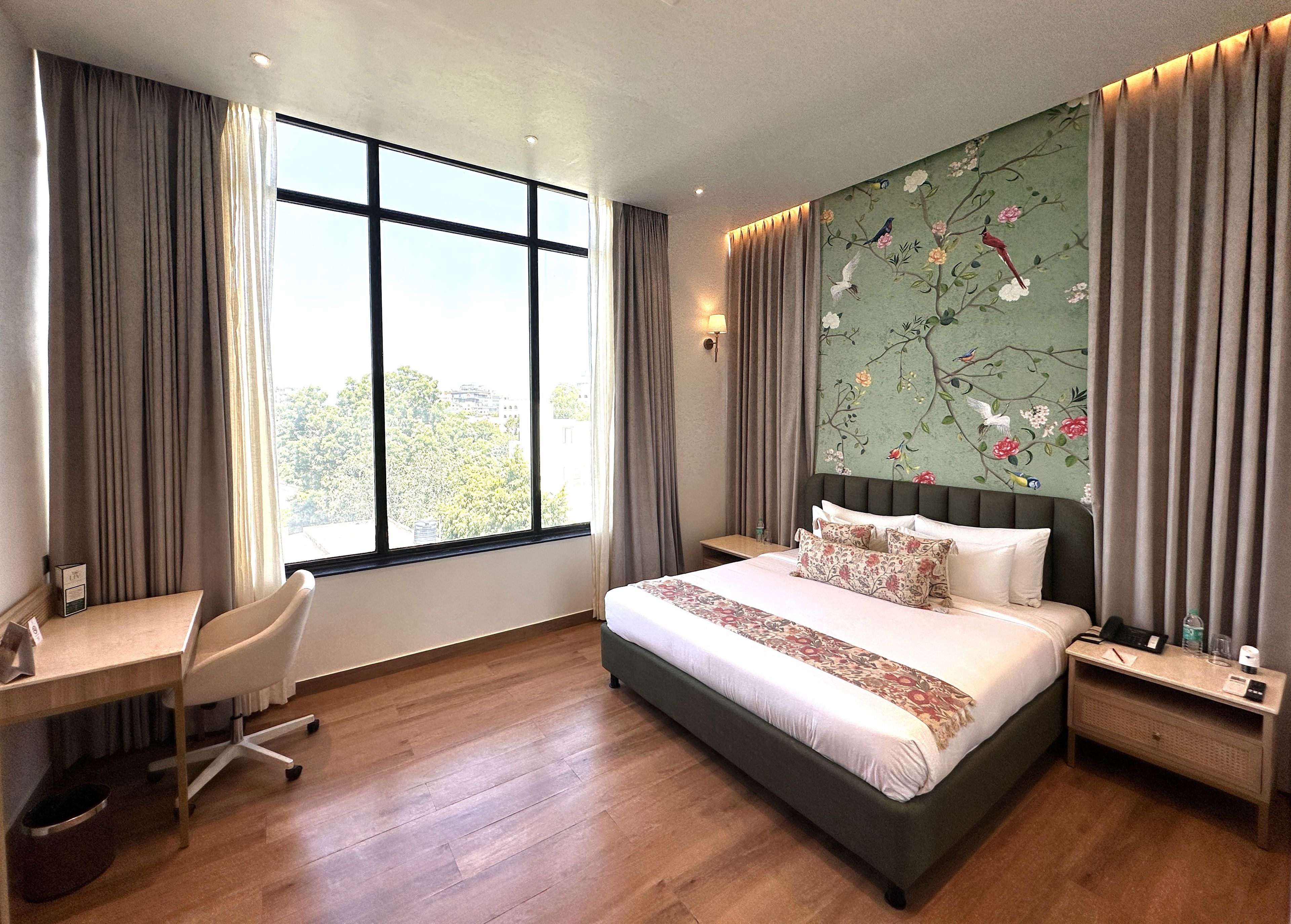Een hotelkamer met een groot bed, een bureau en uitzicht op de stad.