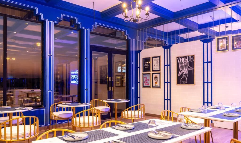 A restaurant interior with blue accents, round tables, and chairs.