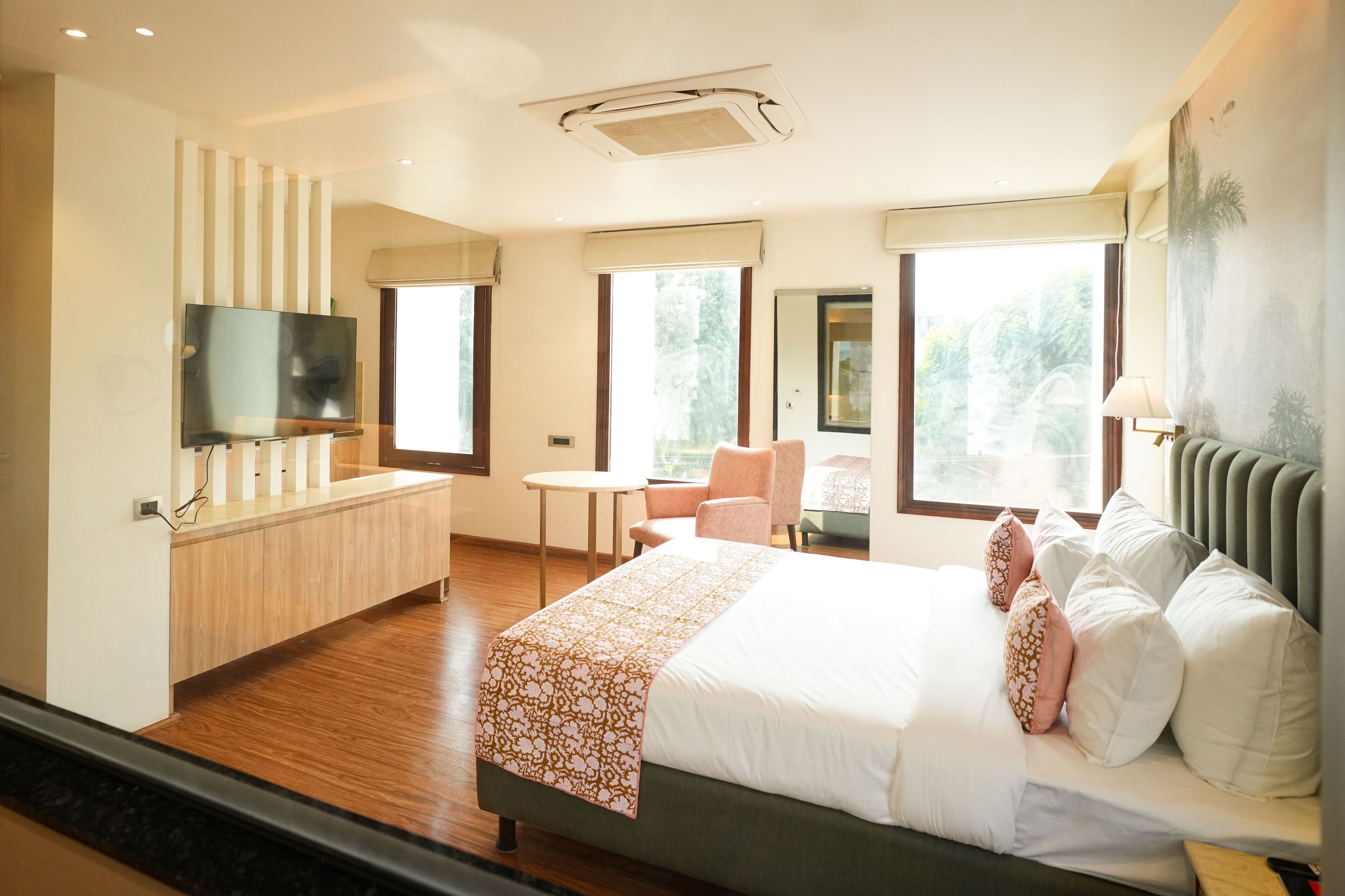 Quarto de hotel com uma cama grande, uma escrivaninha, uma cadeira e uma televisão.