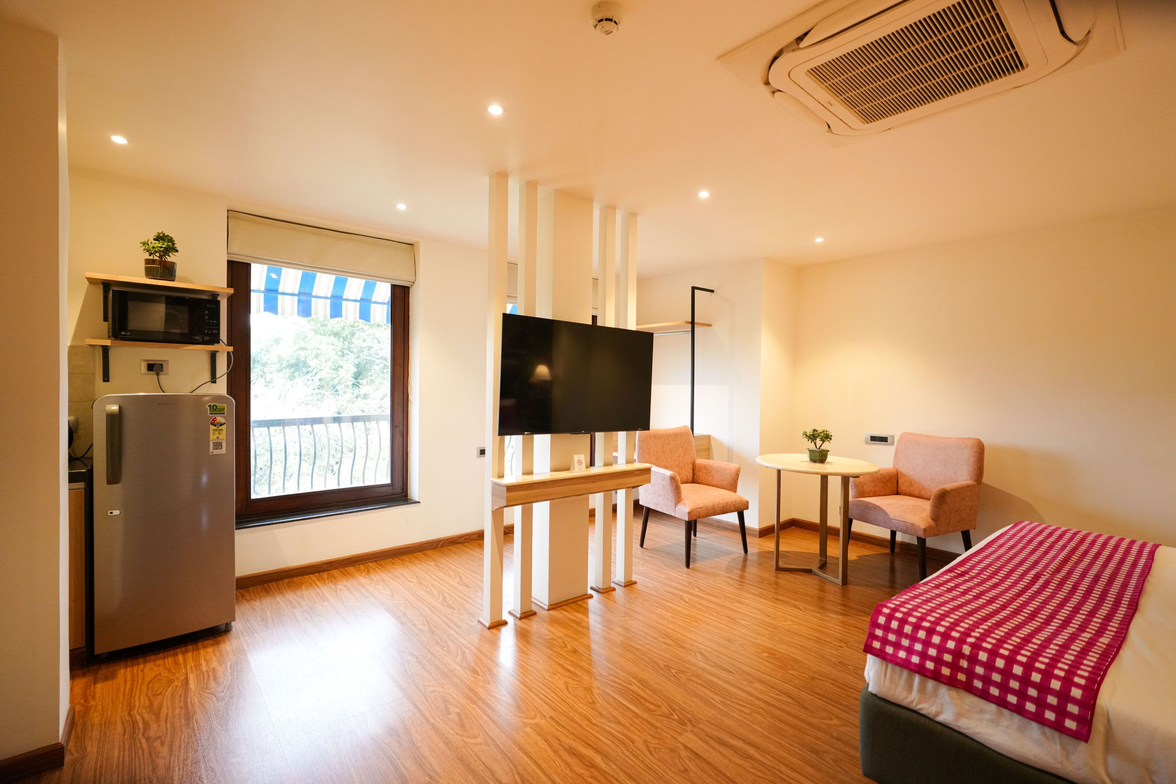 Une chambre d’hôtel équipée d’un lit, d’une télévision, d’une petite table, de deux chaises, d’un four à micro-ondes et d’un réfrigérateur.