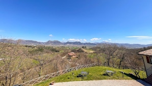 A grassy area with a table and chairs, a small building, and a view of distant mountains. - Amazing apartment in Gubbio with WiFi (Gubbio)