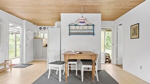 A dining area with a wooden table and chairs, a hanging light fixture, and a wall-mounted shelf with dishes and jars. - Awesome home in Jægerspris with WiFi (Jægerspris)