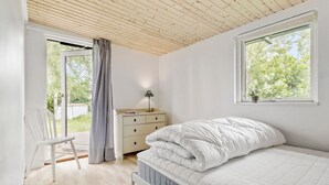 A bedroom with a bed, a nightstand, a chair, a window, and a view of greenery outside. - Awesome home in Jægerspris with WiFi (Jægerspris)