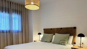 Un letto rifatto con lenzuola bianche, una testiera in legno e due lampade ai lati del letto.