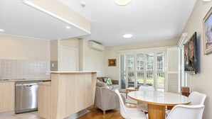 Una cocina moderna con lavavajillas, una isla de madera y un comedor con mesa redonda y sillas blancas.