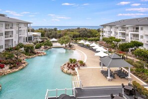 Een resort met een zwembad, ligbedden en uitzicht op de oceaan.