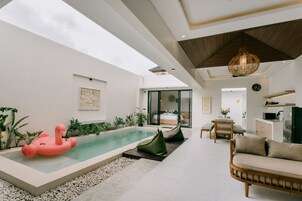 A modern living room with a pool, a sofa, and a dining area.