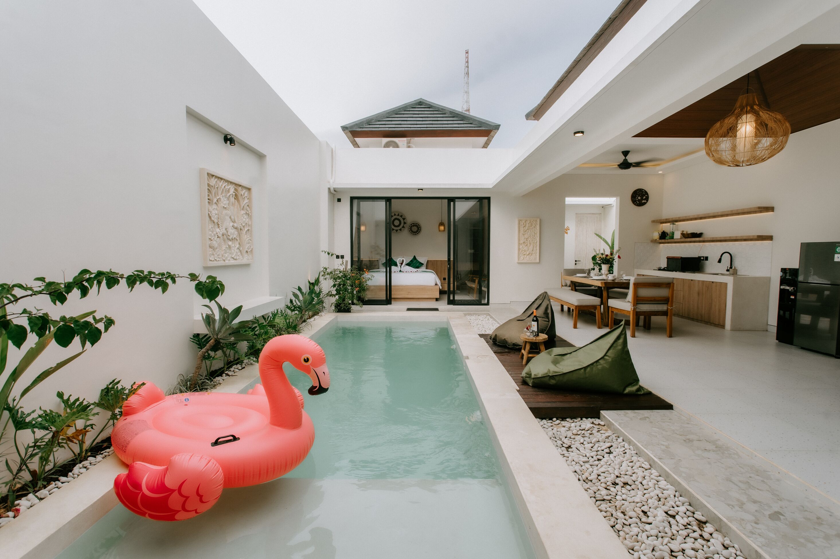 Un intérieur moderne avec une piscine, un flotteur en forme de flamant rose et un coin repas.