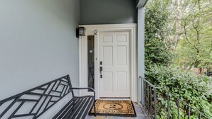 A white door with a number '2' above it, a black metal bench, and a doormat with a number '2' on it.