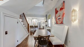 A modern kitchen with white cabinets, a dining area with a white bench, and a staircase leading to another level.