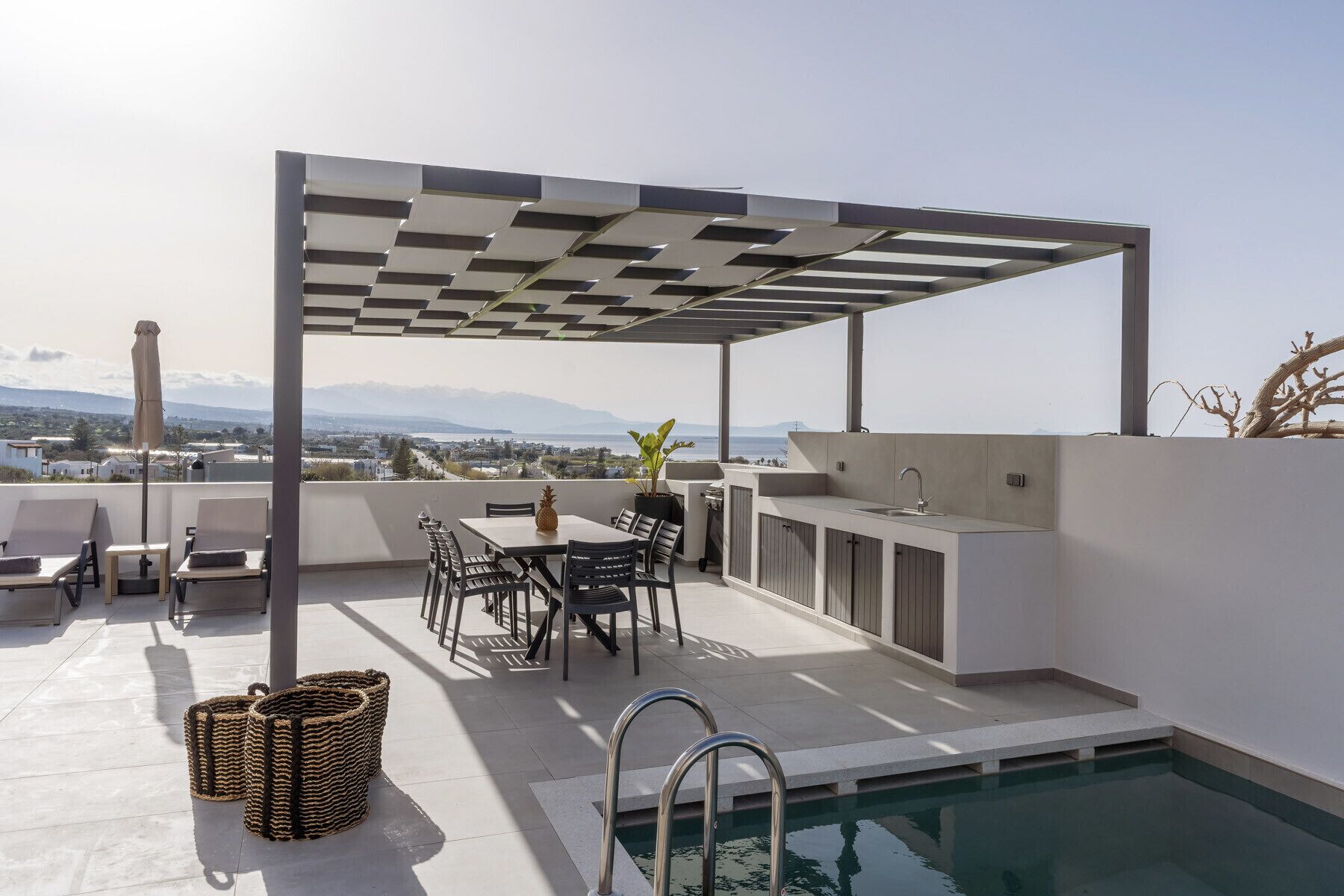 A rooftop terrace with a pool, outdoor seating, and a view of distant mountains.