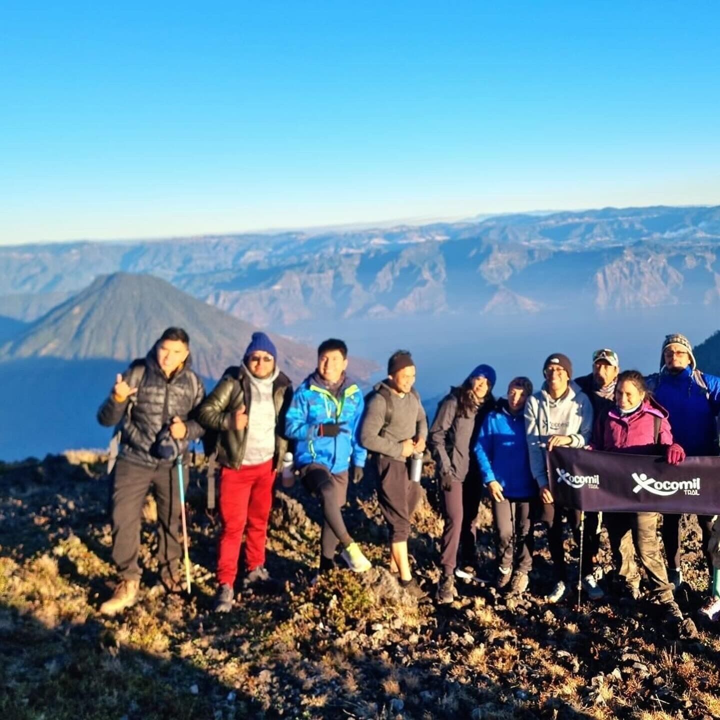 A group of people standing on a rocky terrain with a banner that reads "Xcomil Trial".