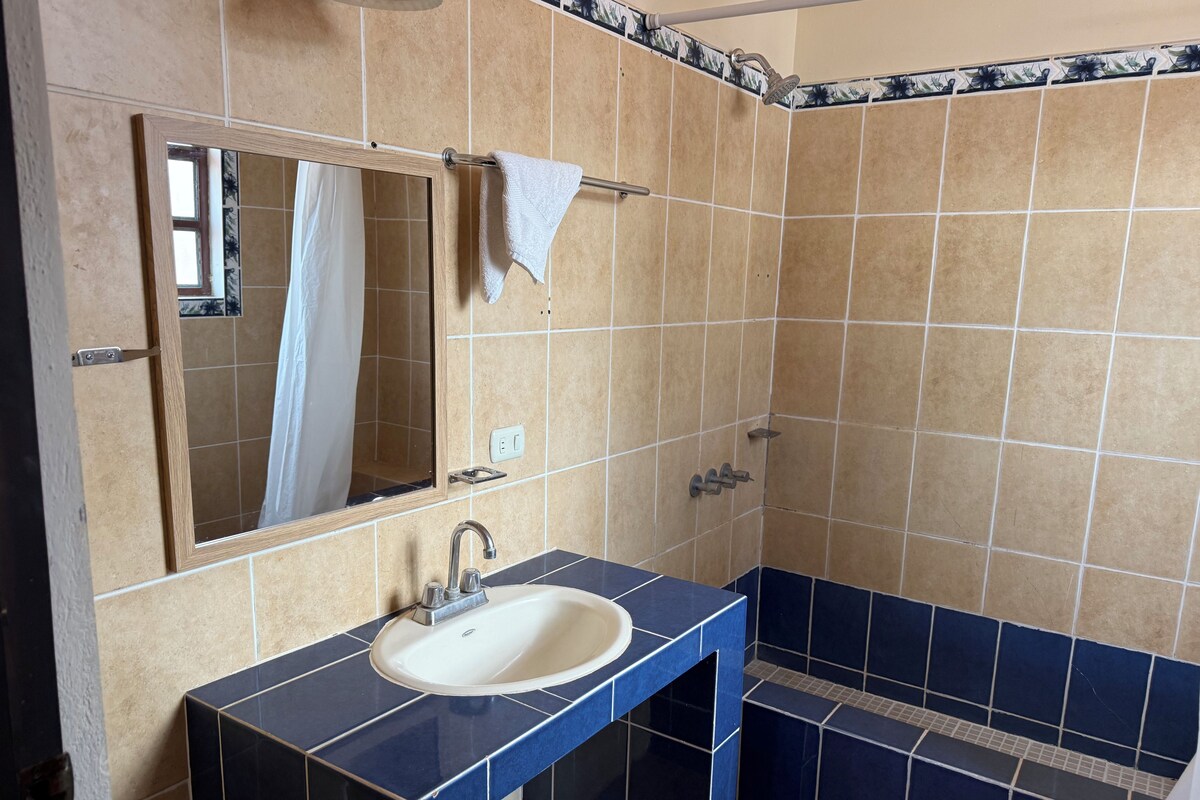 Een badkamer met een wastafel, spiegel en douche.