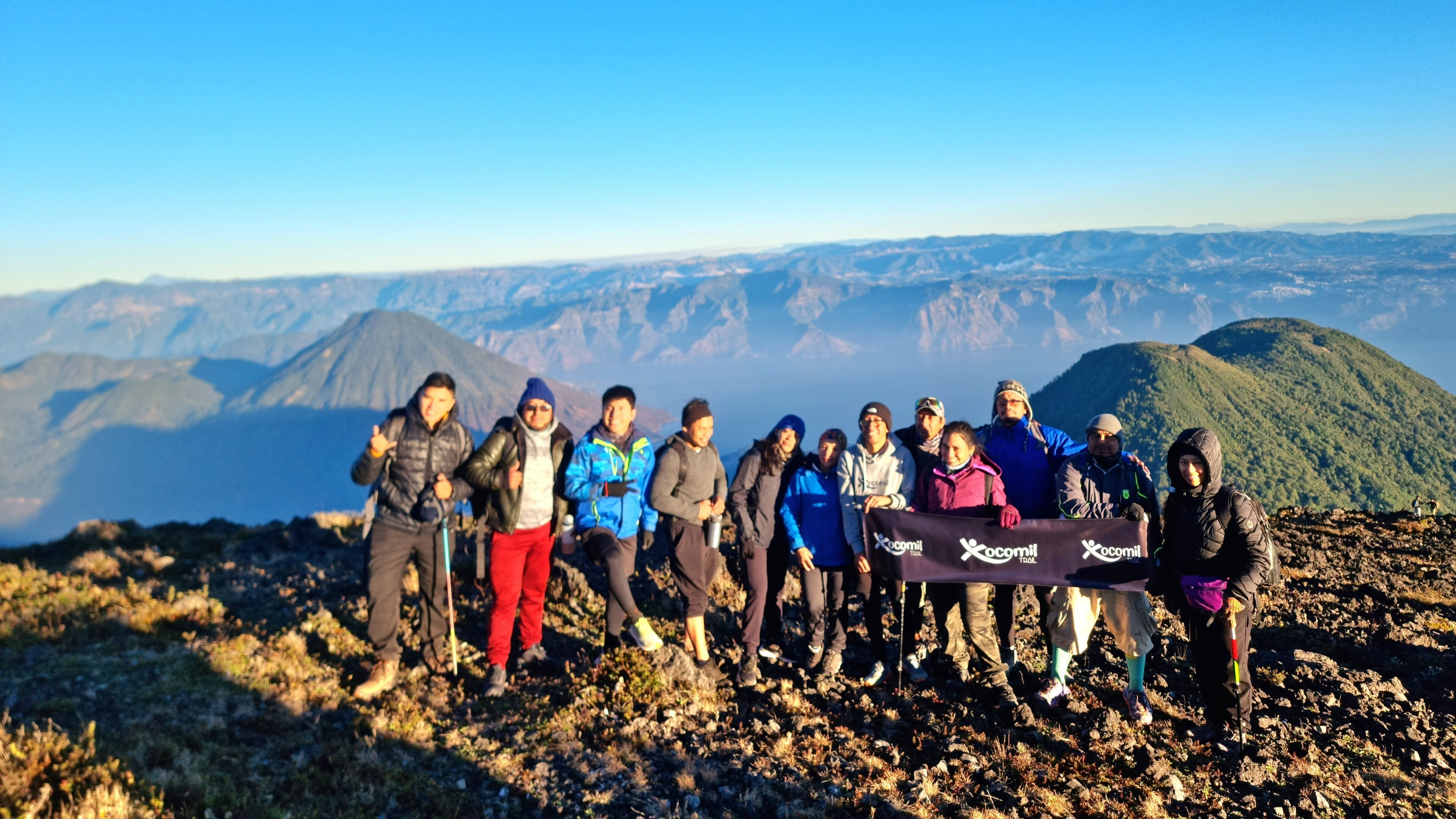 A group of people standing on a rocky terrain with a mountainous backdrop.