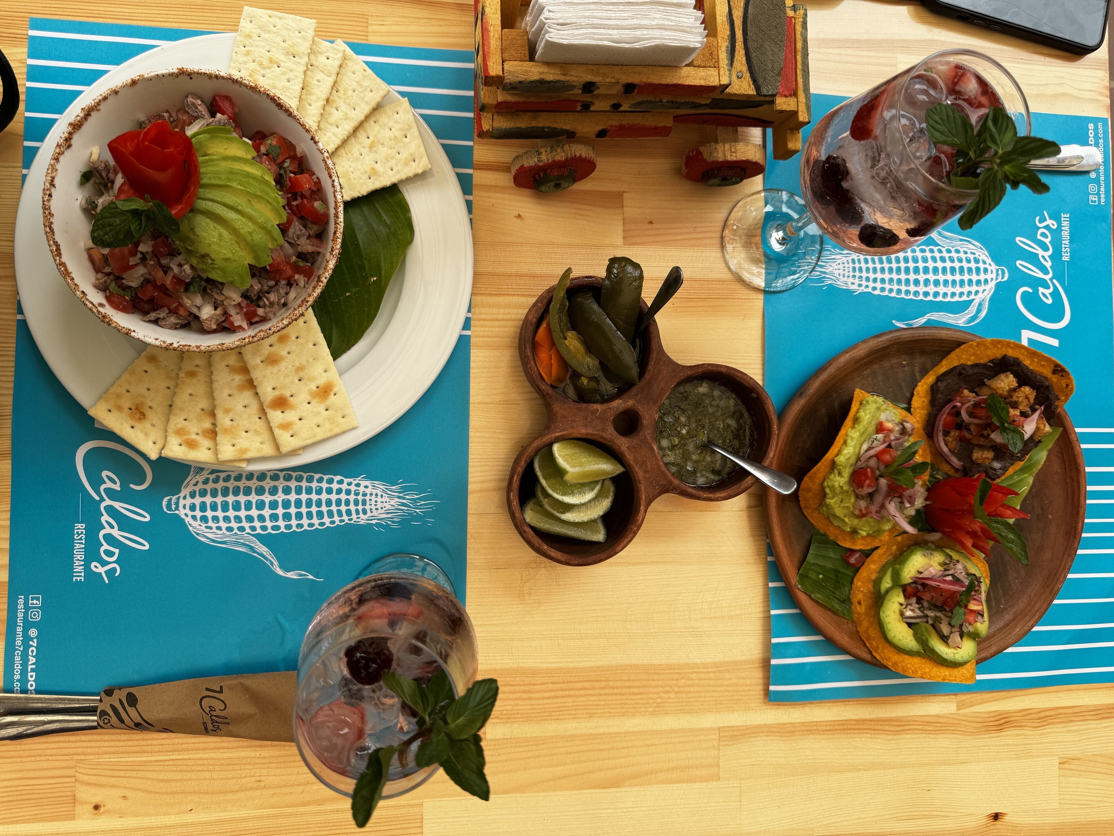 A table with a variety of dishes including tacos, a bowl of salad, and a drink.