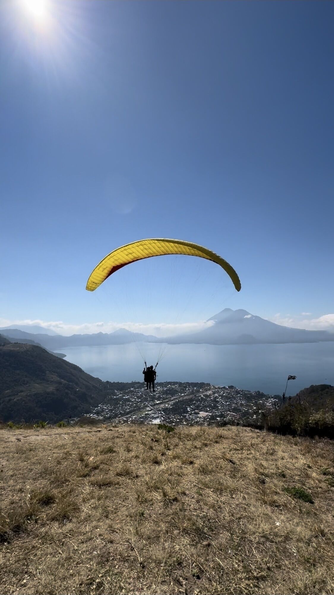A person paragliding over a mountainous landscape with a clear sky.