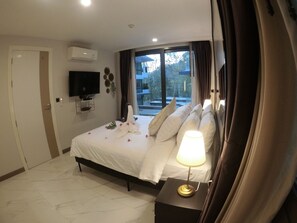 A hotel room with a bed, a bedside lamp, a TV, and a window with curtains.