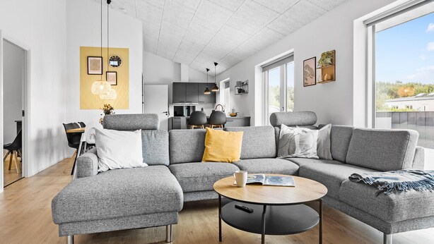 A modern living room with a grey sectional sofa, a round coffee table, and a dining area with a small table and chairs. - Pet friendly home in Sydals with WiFi (Sydals)