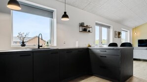A modern kitchen with dark cabinetry, a large window, and pendant lighting. - Pet friendly home in Sydals with WiFi (Sydals)