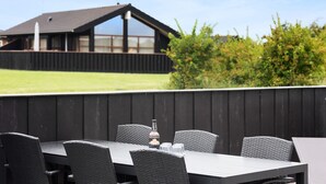 An outdoor dining area with a table and chairs, a bottle of water, and a glass. - Pet friendly home in Sydals with WiFi (Sydals)