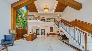 A spacious lobby with a high ceiling, a grand staircase, a reception desk, and a wheelchair-accessible area. - Highland Club (Hatkalangda)