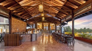 A spacious indoor area with a marble floor, wooden ceiling beams, and a long counter with seating on one side. - Highland Club (Hatkalangda)