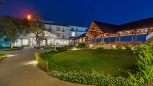 A hotel with a well-lit outdoor area, a covered patio, and a manicured lawn. - Highland Club (Hatkalangda)