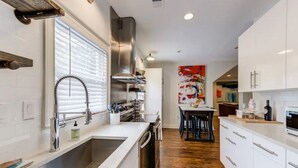 A modern kitchen with white cabinets, stainless steel appliances, and a wooden floor. - Safe, convenient Vacation Rental in Midtown - Sleeps 7 w/3 full bathrooms! (Atlanta)