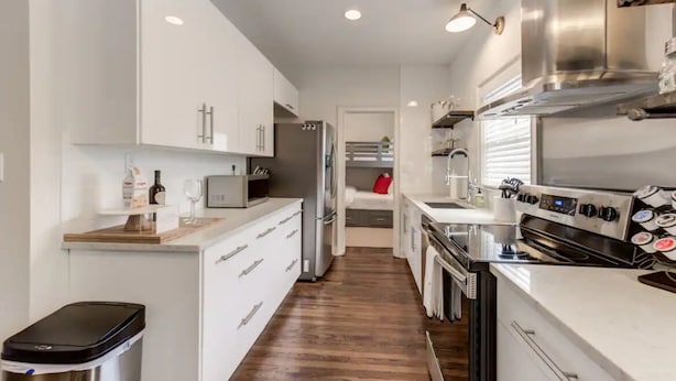 A modern kitchen with white cabinetry, stainless steel appliances, and a wooden floor. - Safe, convenient Vacation Rental in Midtown - Sleeps 7 w/3 full bathrooms! (Atlanta)