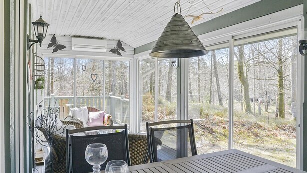 Ein Wintergarten mit Tisch und Stühlen, großen Fenstern und hängenden Laternen.
