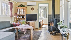Ein gemütliches Wohnzimmer mit Sofa, Fernseher, Holzschrank und Kamin.