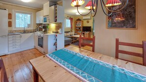 Eine kompakte Küche mit Essbereich, einem Holztisch mit gemustertem Tischläufer und einer Deckenleuchte mit roten Lampenschirmen.