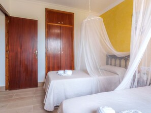 Ein Hotelzimmer mit zwei Betten, einem Holzschrank und einer gelben Wand.