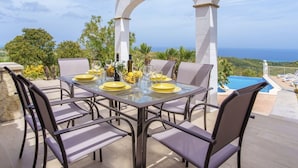An outdoor dining area with a table set for four, overlooking a pool and the ocean. - Cana Molí, ecohouse with sea views (Arta)