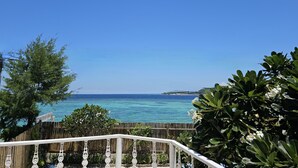 A balcony with a view of the ocean and a wooden fence. - VILLA AURORA (Gili Meno)
