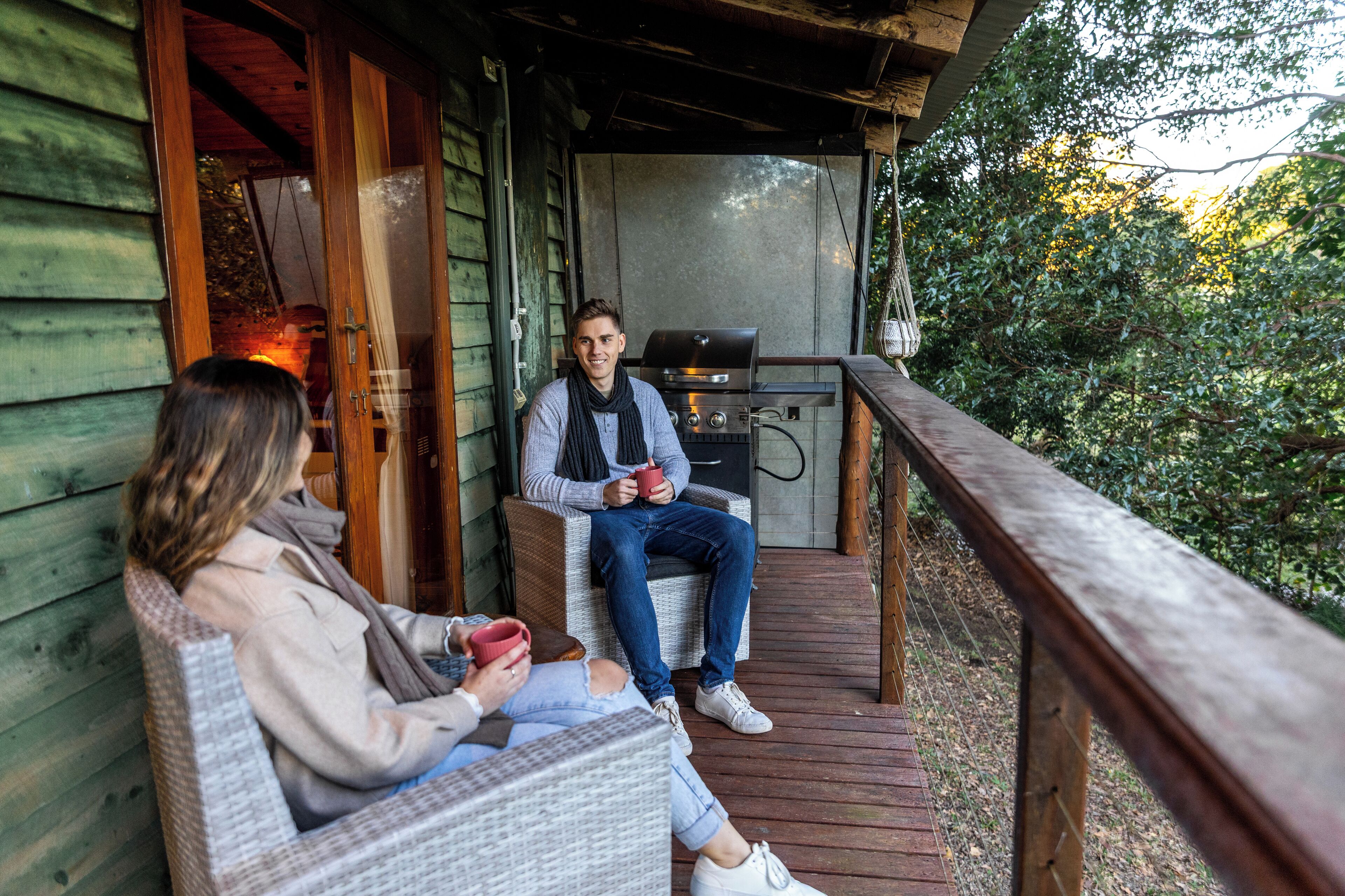Une terrasse en bois avec des meubles en osier et un barbecue.