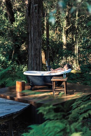 A rustic outdoor bathtub in a forest setting. -  Kanimbia Cottages (Coolabine)