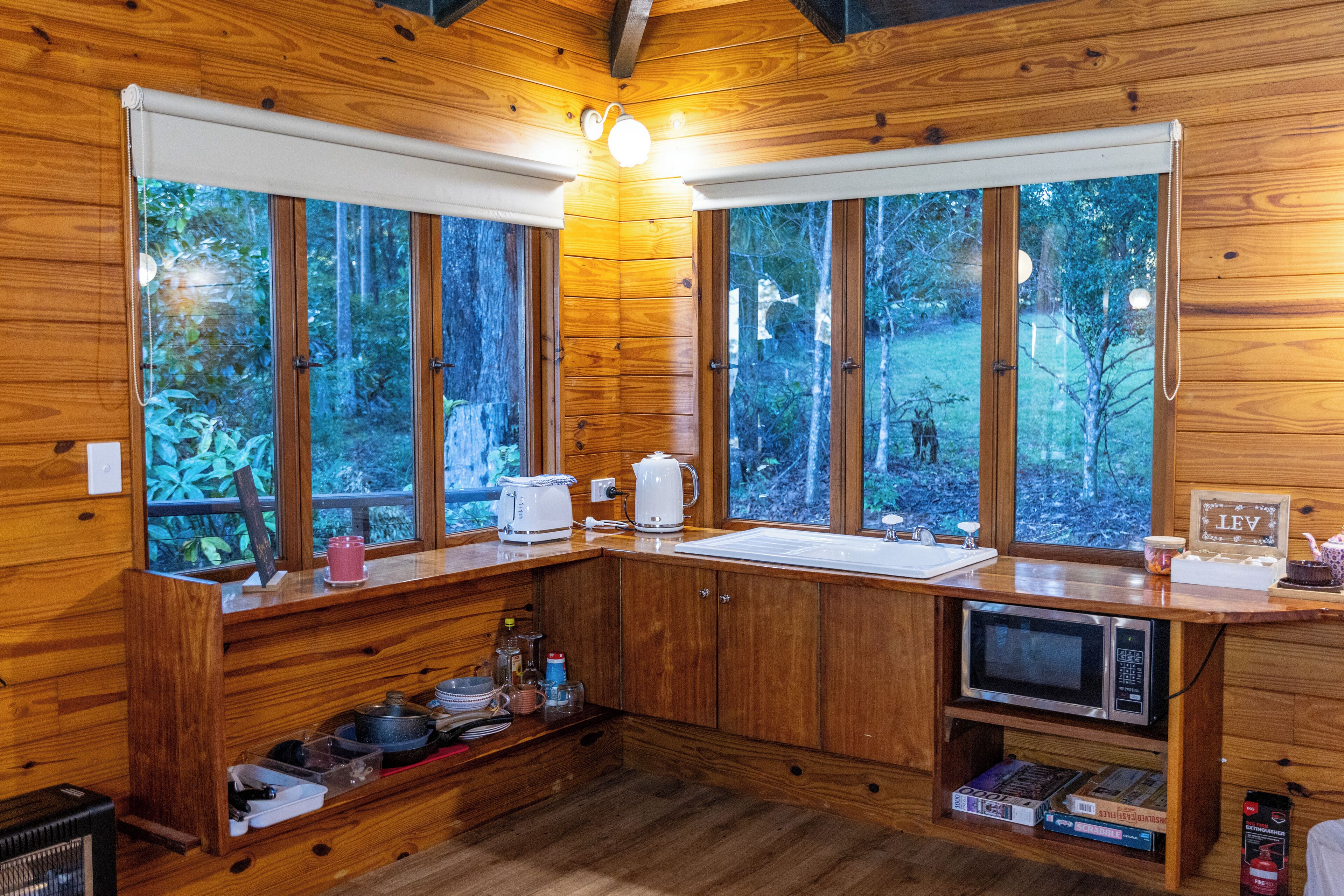 Een houten keukentje in een chalet met grote ramen, een magnetron en een spoelbak.