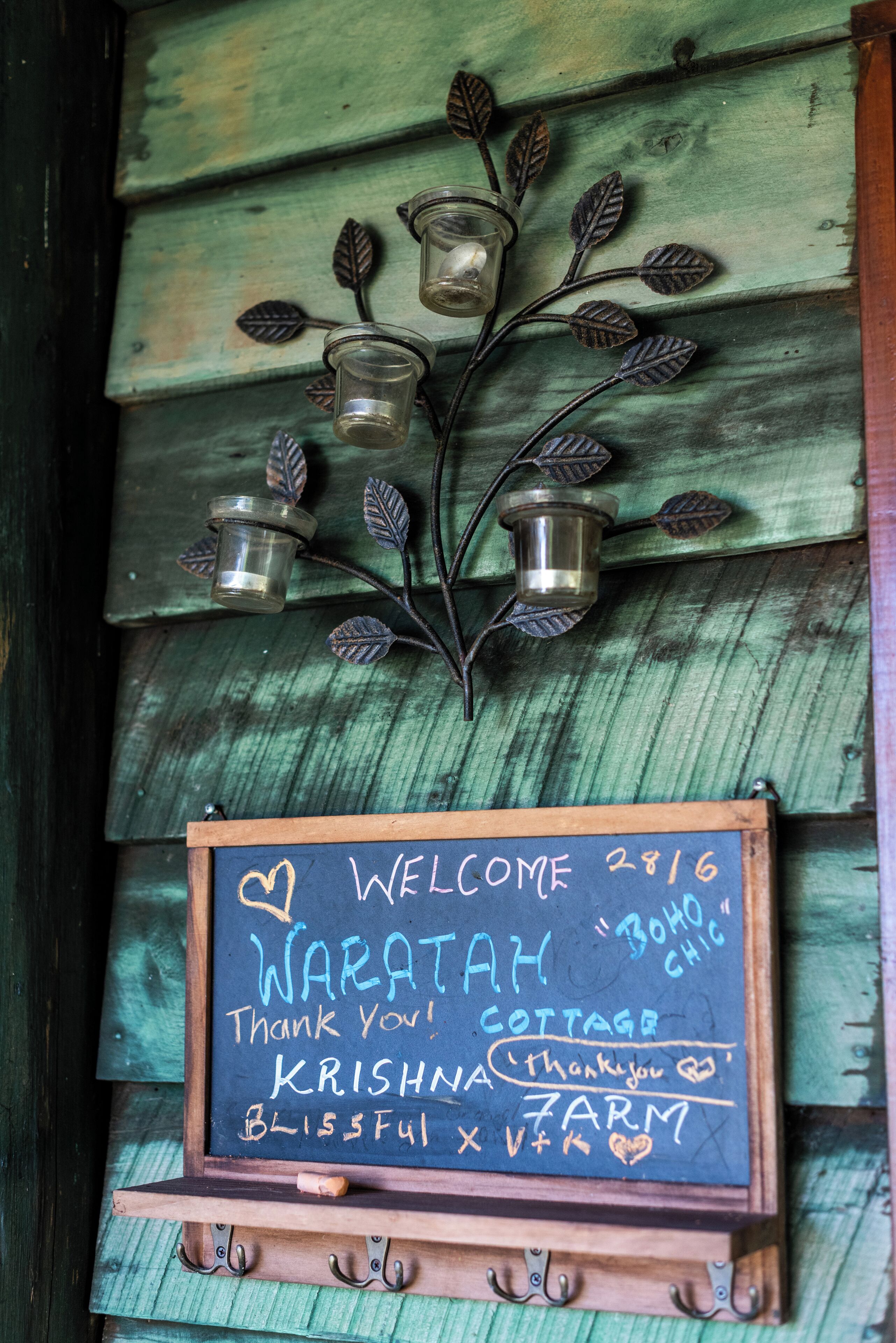 A chalkboard sign with a rustic wooden background, featuring a welcome message, a thank you note, and the name 'Krishna Bliss Farm'.