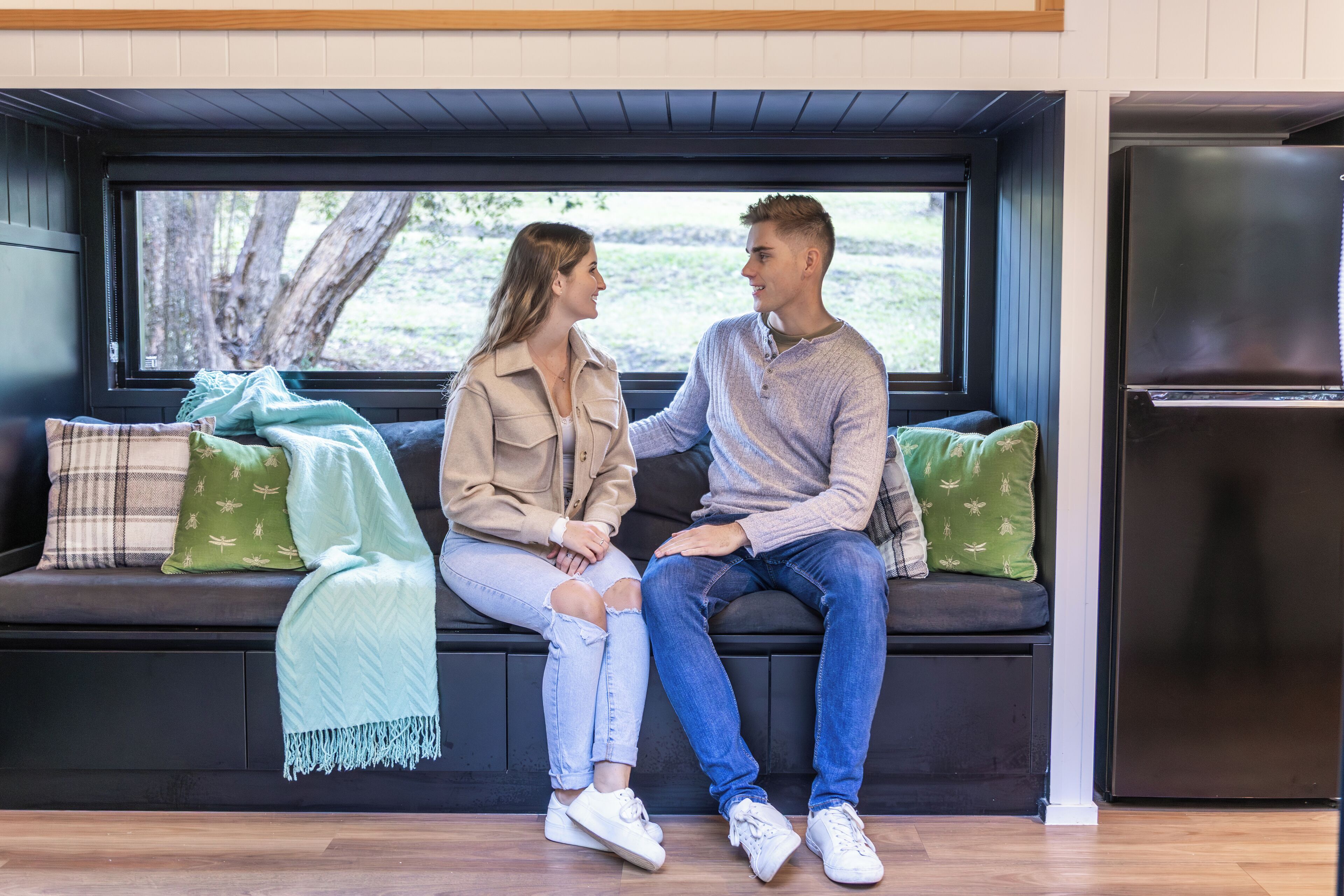 A couple sitting on a bench with a view of a tree outside.