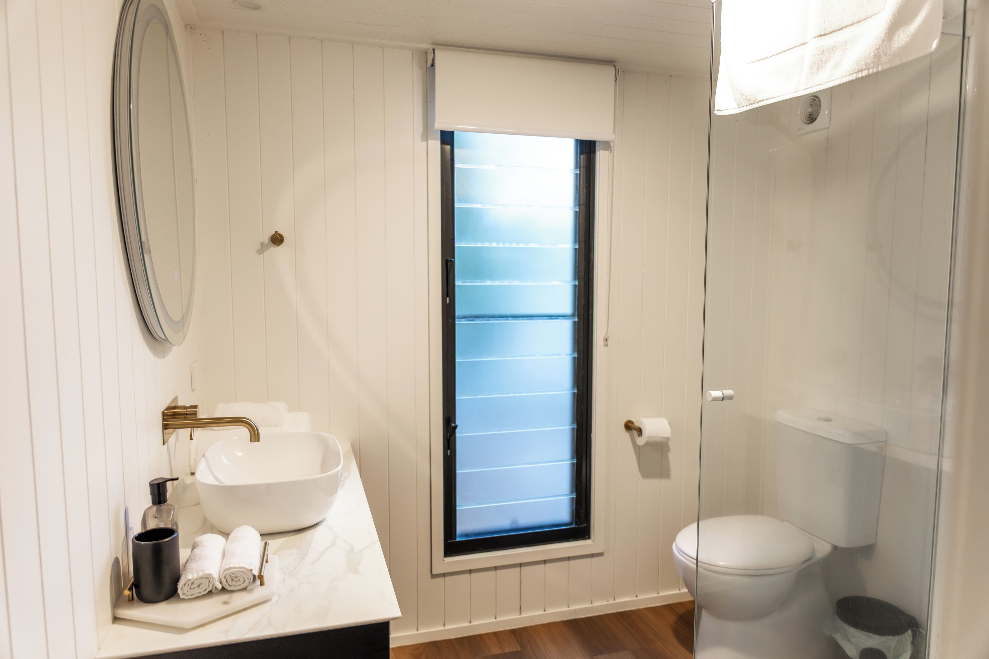 A bathroom with a white sink, mirror, and toilet.